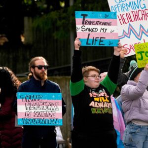 People wave signs during a pro-transgender rights rally outside of Seattle Children's Hospital after the institution postponed some gender-affirming surgeries for minors following an executive order by President Donald Trump, Sunday, Feb. 9, 2025, in Seattle. (AP Photo/Lindsey Wasson)